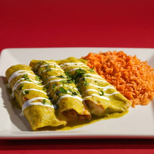 Three green enchiladas drizzled with crema and cilantro, served with a side of orange rice.